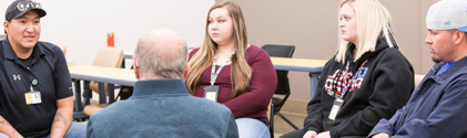 Group of students sitting around having a group conversation with a professor